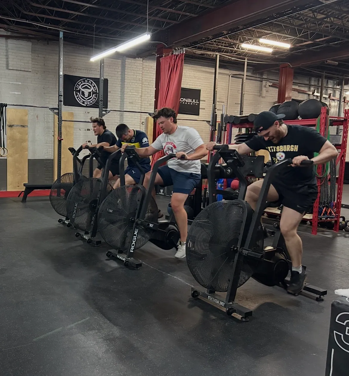 Four athletes pushing hard on the bikes during a HIIT class at PRO1