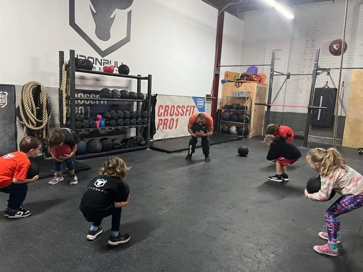 Kids squatting with medicine balls in a supervised class